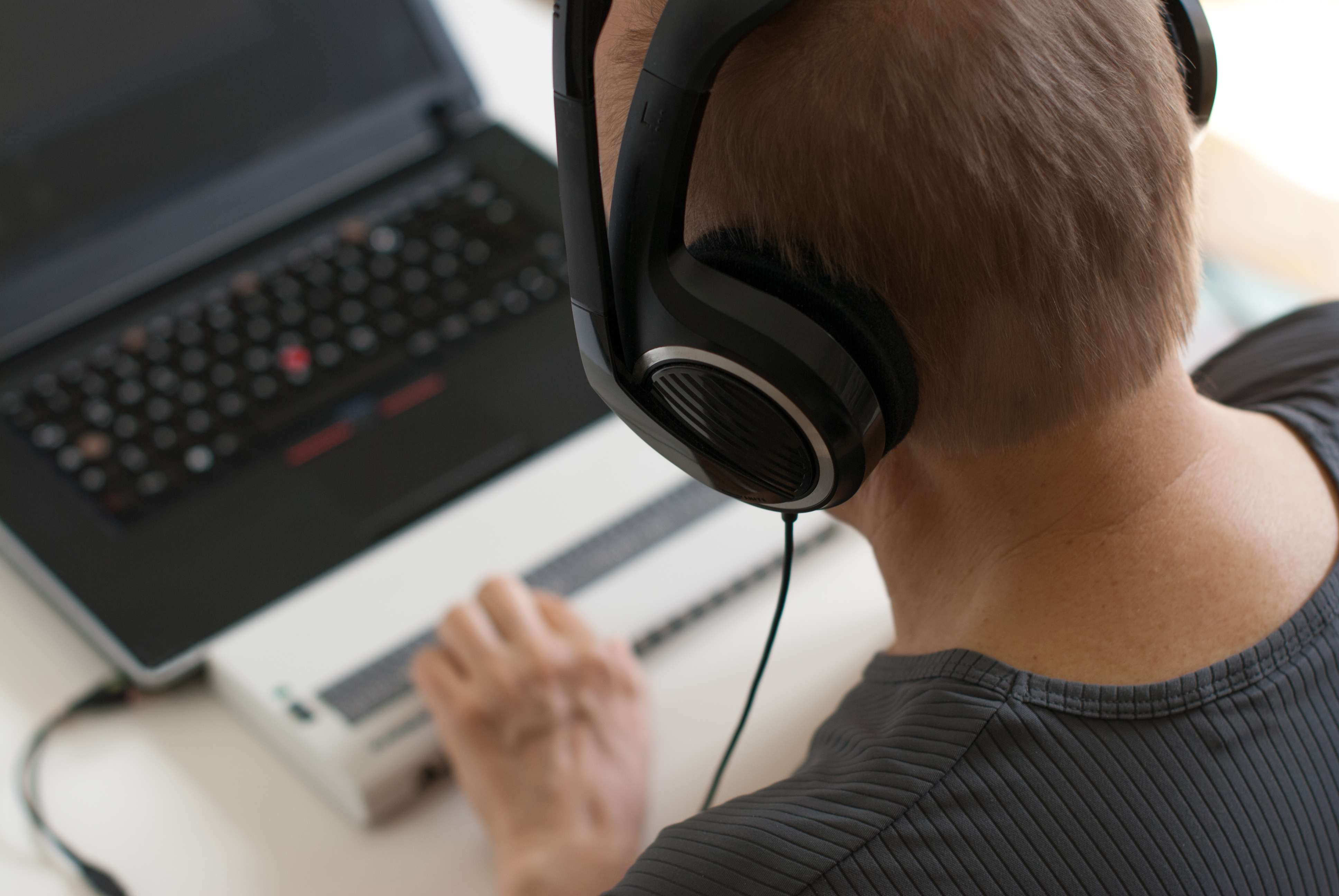 Blind person working on computer with screen reader and braille